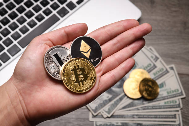 İstanbul, Turkey - February 12, 2018: A hand holding Bitcoin, Litecoin and Ethereum memorial coins on a desk. Bitcoin, Litecoin and Ethereum are crypto currencies and worldwide payment systems.
